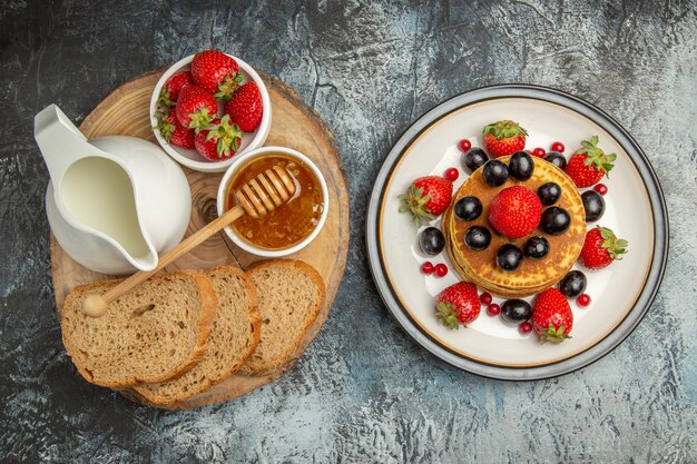 Top view yummy pancakes with fresh fruits and bread on light