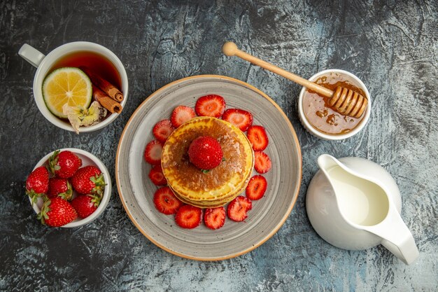 Vista dall'alto gustosi pancake con frutta e tazza di tè in luce