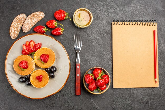 Top view yummy pancakes with fruits on a dark