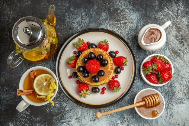 Вид сверху вкусные блины с фруктами и чаем на светлом полу сладкий фруктовый завтрак