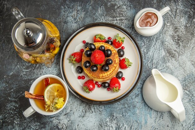 Top view yummy pancakes with fruits and tea on a light