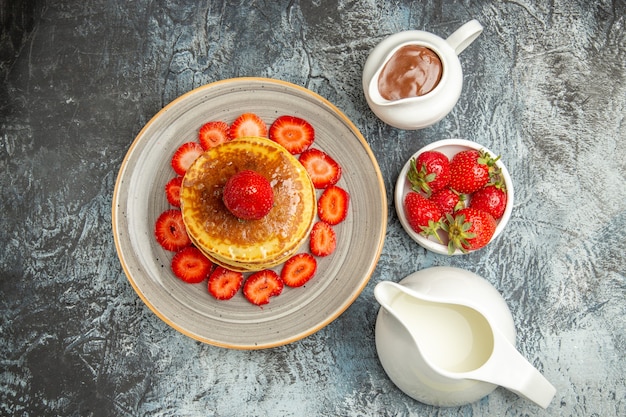 Вид сверху вкусные блины с медом и клубникой на свете