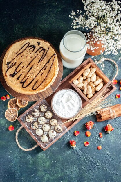 Top view yummy pancakes with nuts and milk on dark-blue background morning pie dessert sweet cake breakfast milk