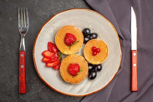 Top view yummy pancakes with olive and fruits on dark