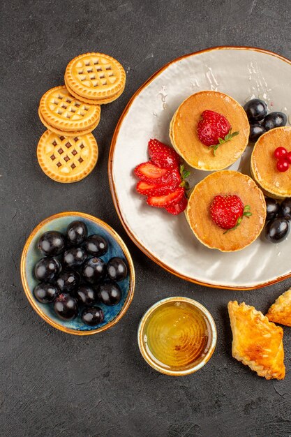 Top view yummy pancakes with olives and fruits on dark