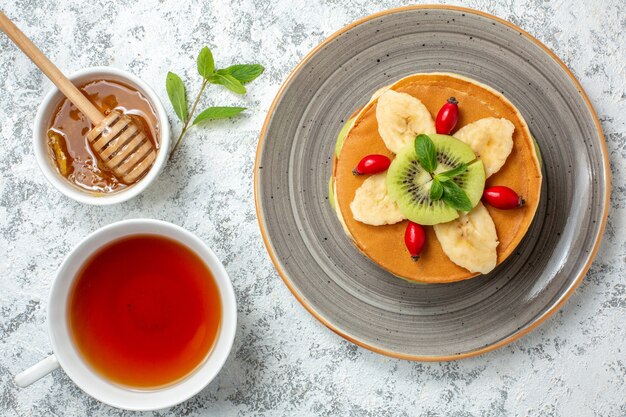 흰색 표면 과일 달콤한 디저트 조식 컬러 케이크에 얇게 썬 과일과 차 한 잔을 곁들인 맛있는 팬케이크