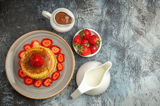 ライトにイチゴと蜂蜜を添えたトップビューのおいしいパンケーキ