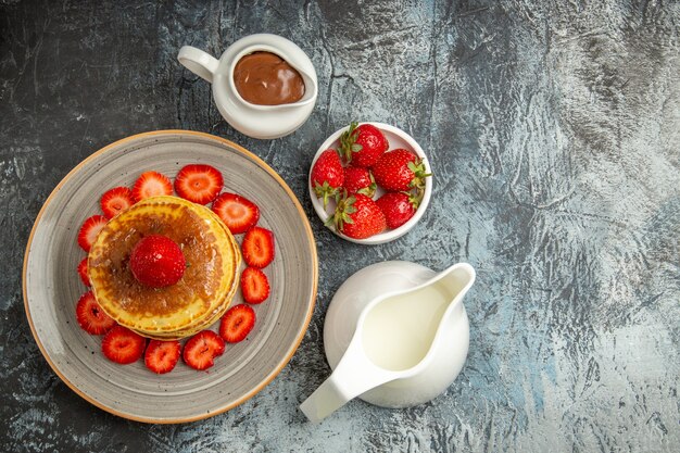 Top view yummy pancakes with strawberries and honey on light