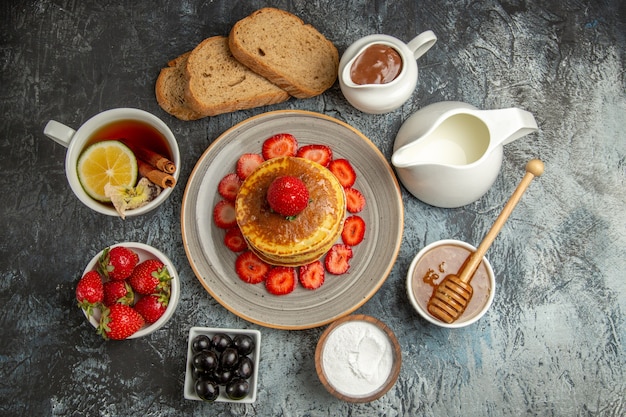 Top view yummy pancakes with tea and fruits on light