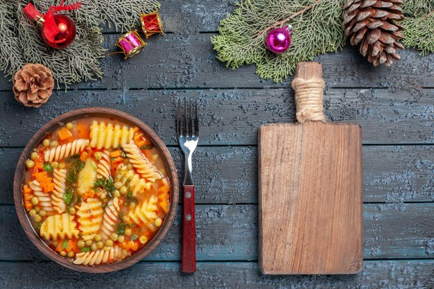 Вид сверху вкусная паста-суп из спиральной итальянской пасты с зеленью на темно-синем столе кухня паста цветное блюдо ужин