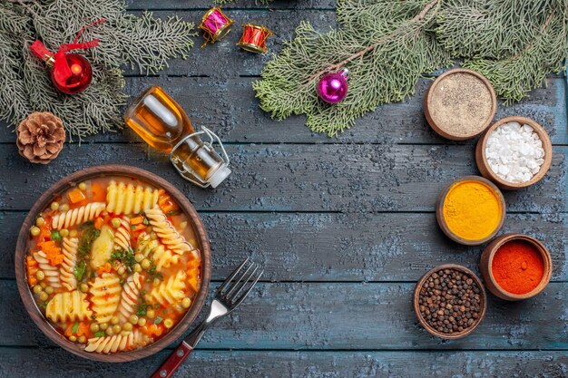 Top view yummy pasta soup from spiral italian pasta with seasonings on dark-blue desk cuisine pasta soup dinner color dish