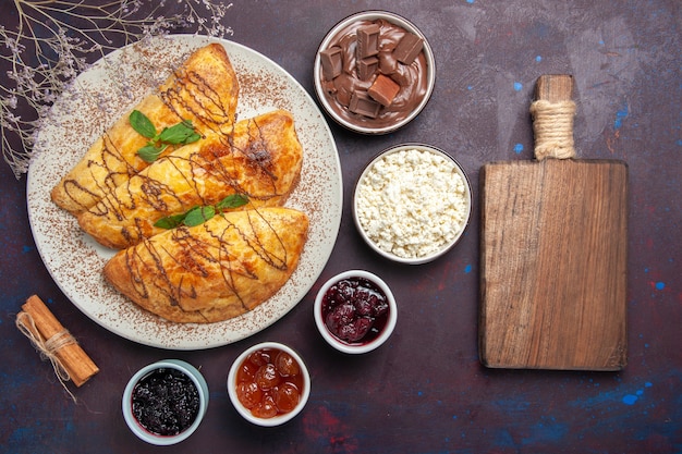 Top view yummy pastries with jam and cottage cheese on dark background pastry sweet bake cake sugar cookie