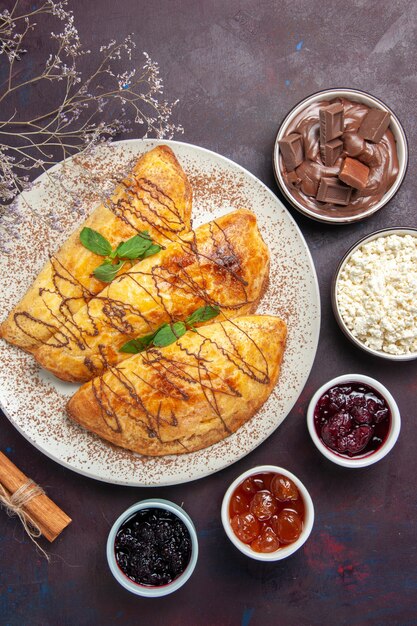 Top view yummy pastries with jam and cottage cheese on a dark background pastry sweet bake tea cake sugar cookie