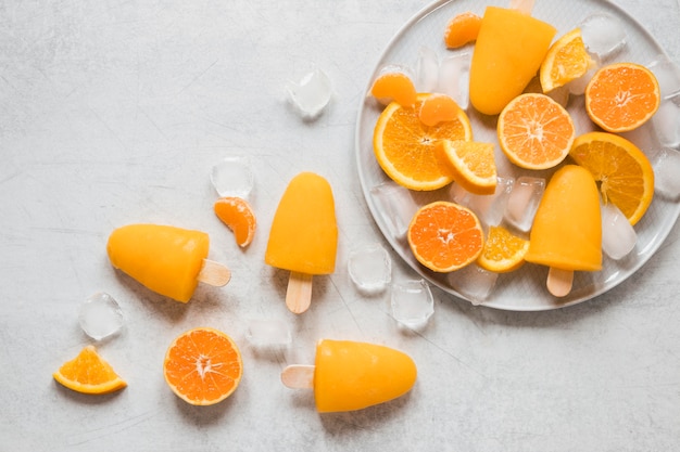 Free photo top view of yummy popsicles on plate with ice and orange