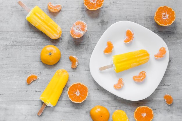 Вид сверху вкусного фруктового мороженого на тарелке с апельсином