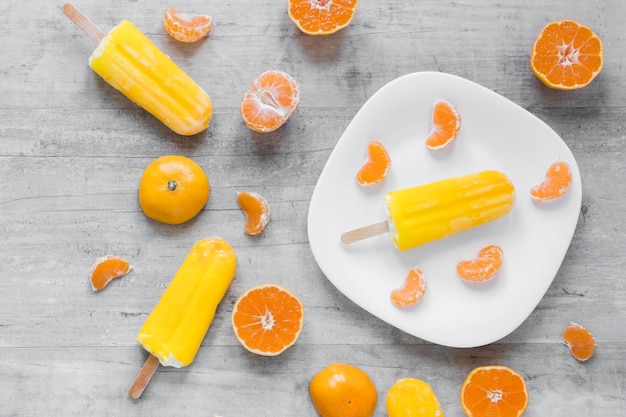 Top view of yummy popsicles on plate with orange