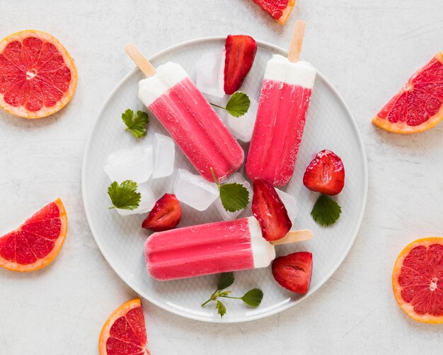 Top view of yummy popsicles on plate with red grapefruit