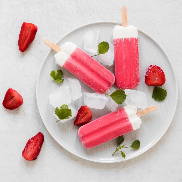 Top view of yummy popsicles with mint and strawberries