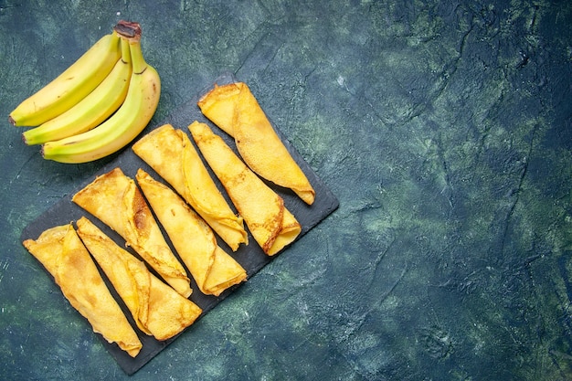 Top view yummy rolled pancakes with bananas on dark background cake dough hotcake color meal pastry sweet pie meat free space