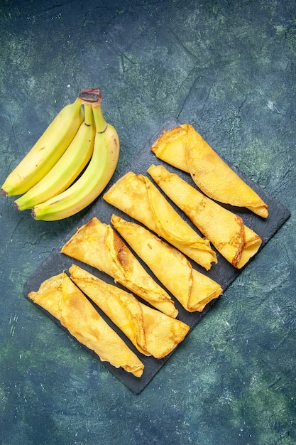 Top view yummy rolled pancakes with bananas on dark background cake dough hotcake meal pastry sweet pie meat