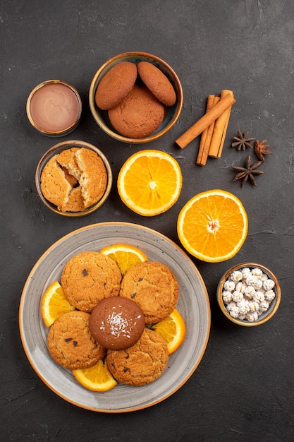 Free photo top view yummy sand cookies with fresh sliced oranges on dark background fruit biscuit sweet cookie citrus sugar