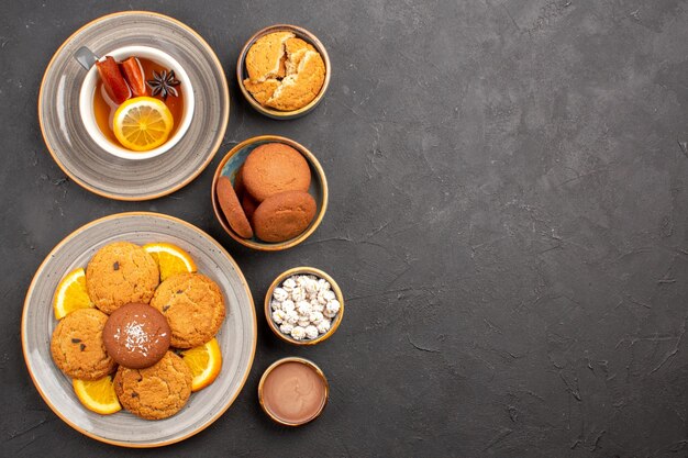 Top view yummy sand cookies with sliced oranges and cup of tea on dark background fruit citrus biscuit sweet cake cookie