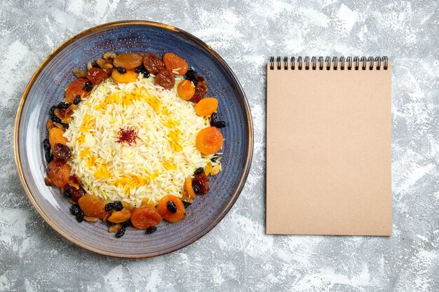 Top view yummy shakh plov cooked rice dish with raisins inside plate on a light white