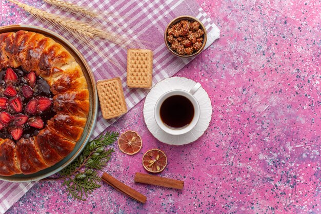 Top view yummy strawberry pie fruity cake with cup of tea on pink