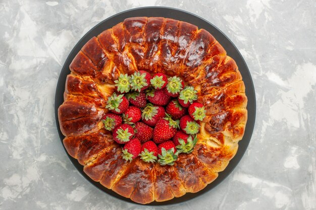 Вид сверху вкусного клубничного пирога со свежей красной клубникой на белой поверхности