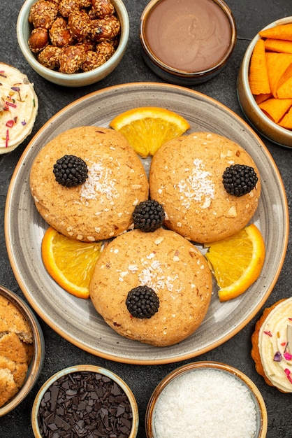 Foto gratuita vista dall'alto deliziosi biscotti di zucchero con fette d'arancia e cips su superficie grigio scuro biscotti biscotto dolce torta di tè