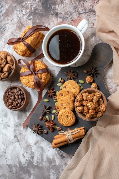 Top view yummy sweet biscuits with coffee seeds and cup of coffee on light table