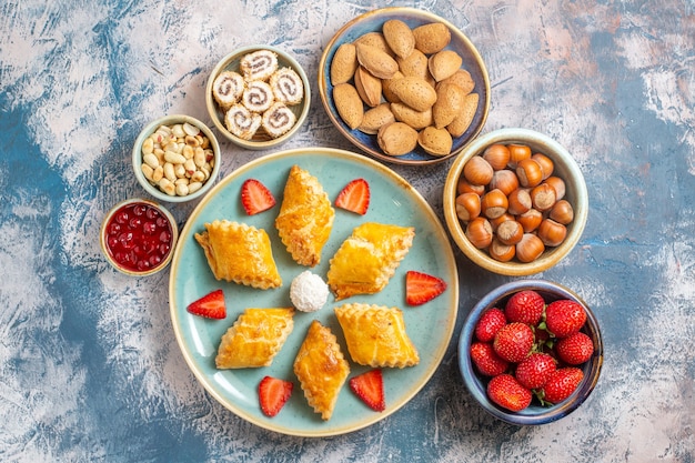 Top view yummy sweet cakes with fruits and nuts on blue background