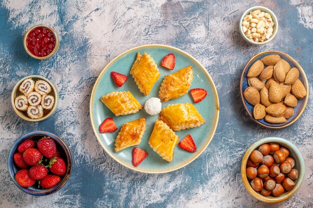 Top view yummy sweet cakes with nuts on blue background