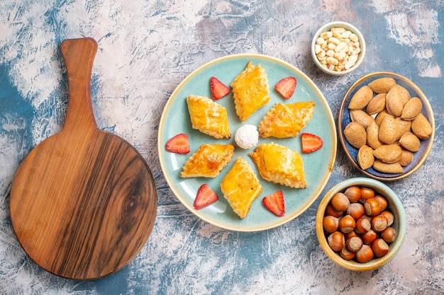 Top view yummy sweet cakes with nuts on blue background