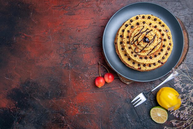 Вид сверху вкусные сладкие блины с шоколадной глазурью на темной поверхности