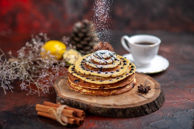 Top view yummy sweet pancakes with tea on dark surface