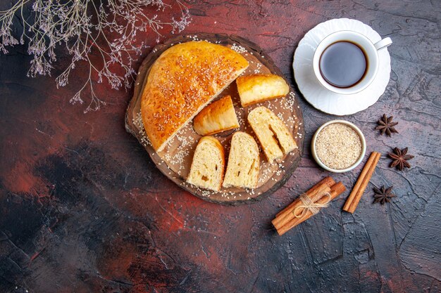 Top view yummy sweet pastry with cup of tea on dark desk