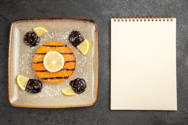 Top view yummy sweet pie with chocolate sauce and lemon slices on grey desk cake pie biscuit dough sweet cookie