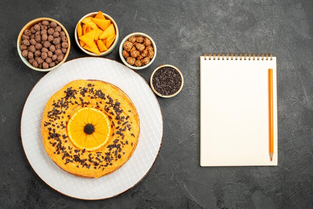 Вид сверху вкусный сладкий пирог с дольками апельсина на серой поверхности бисквитный десерт сладкий пирог торт чай