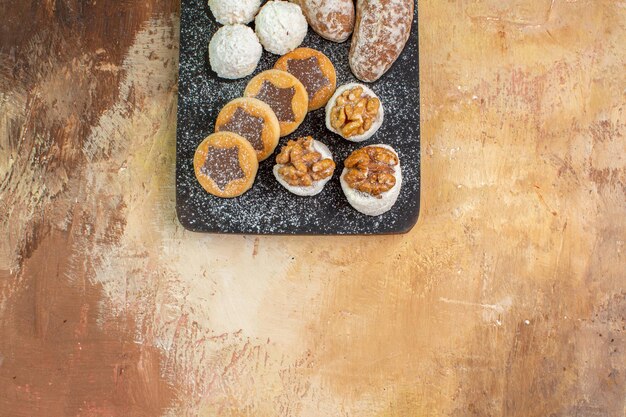 Top view yummy sweets with cookies on wooden desk