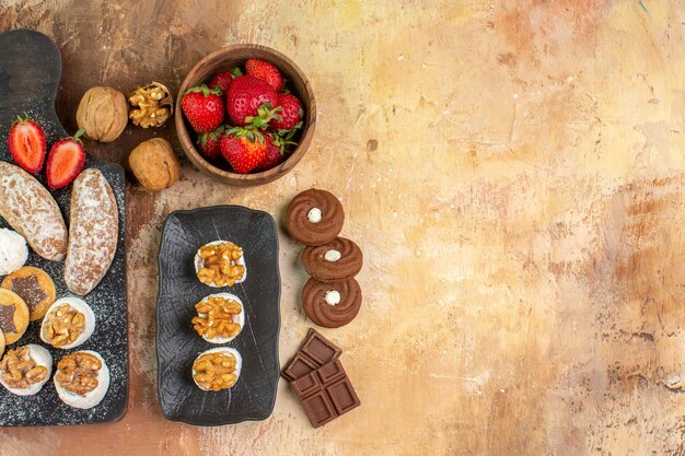 Top view yummy sweets with fruits candies and cookies on wooden desk