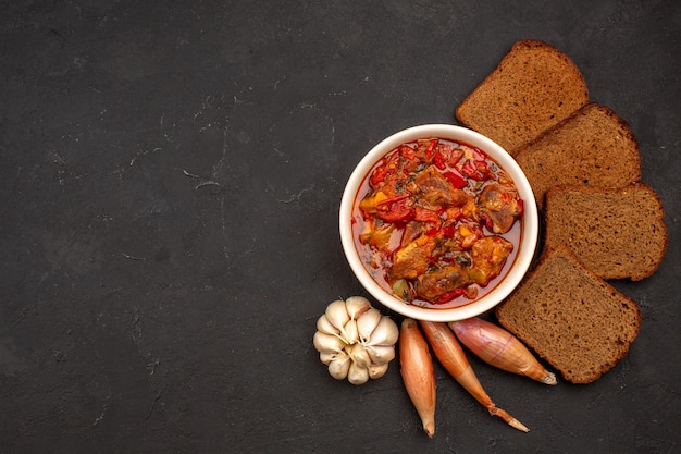 Top view yummy vegetable soup with dark bread loafs on dark