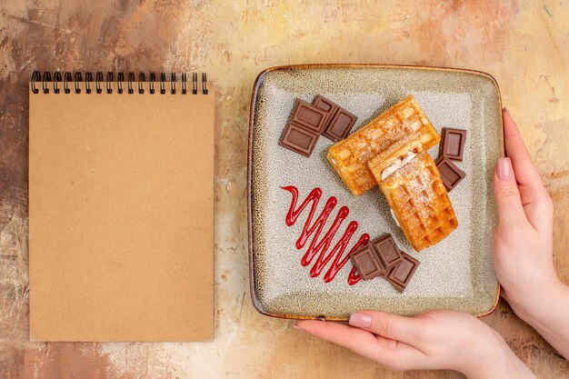 Top view yummy waffle cakes with chocolate bars on a brown background