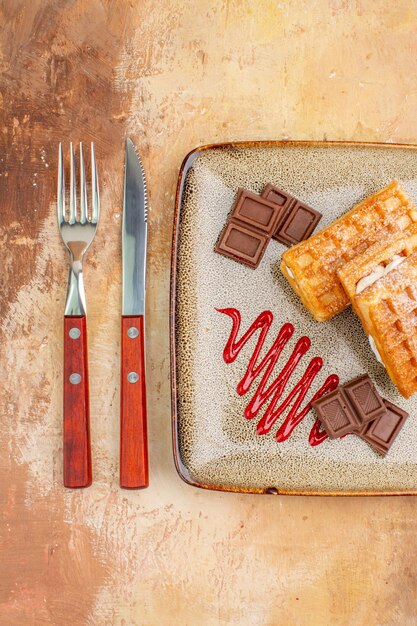 Top view yummy waffle cakes with chocolate bars on a brown background