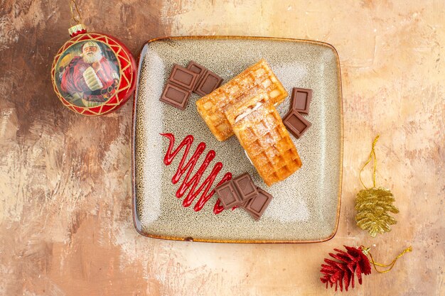 Top view yummy waffle cakes with chocolate bars on brown background