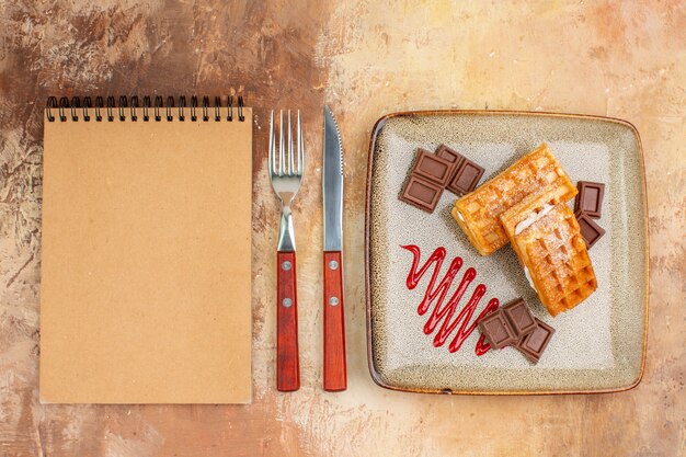 Top view yummy waffle cakes with chocolate bars on brown background