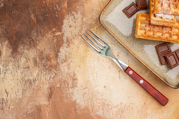 茶色の背景にチョコレートバーとトップビューおいしいワッフルケーキ