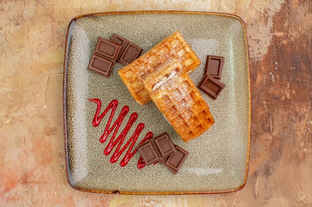 茶色の背景にチョコレートバーとトップビューおいしいワッフルケーキ