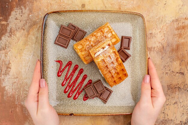 茶色の背景にチョコレートバーとトップビューおいしいワッフルケーキ