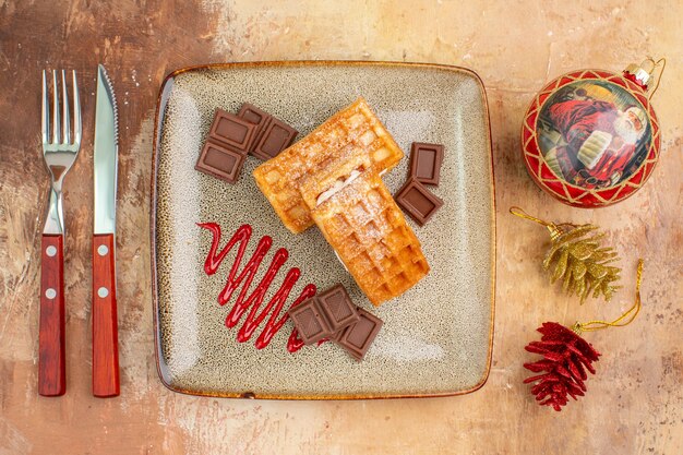 Top view yummy waffle cakes with chocolate bars on the brown background